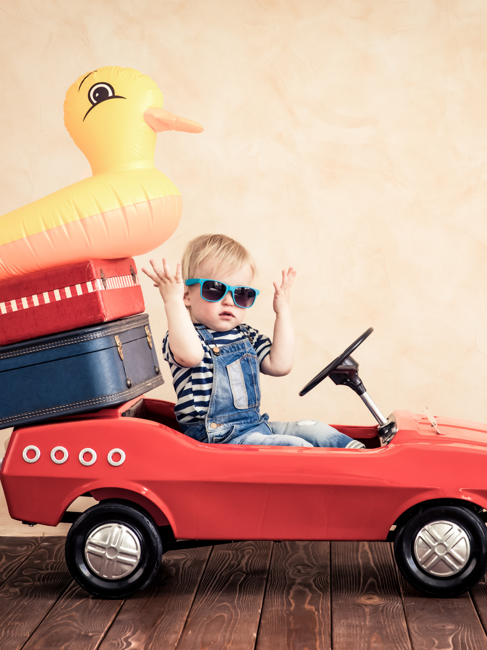 Toddler in a toy car with suitcases