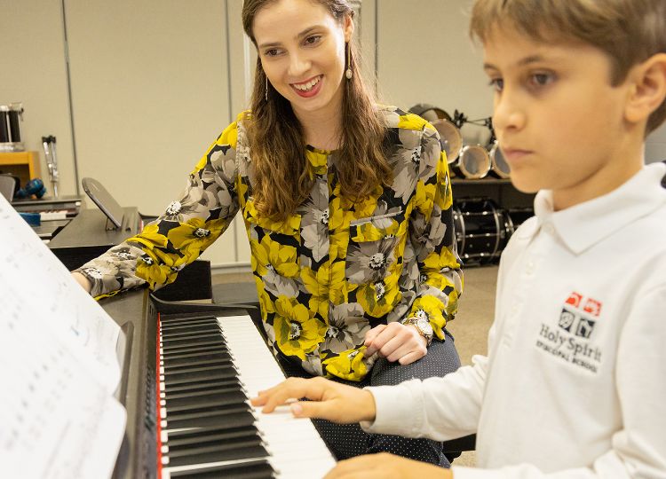 Music teacher with a student at a piano